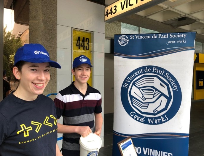 Vinnies Youth Members standing by a Vinnies banner and collecting money for Vinnies